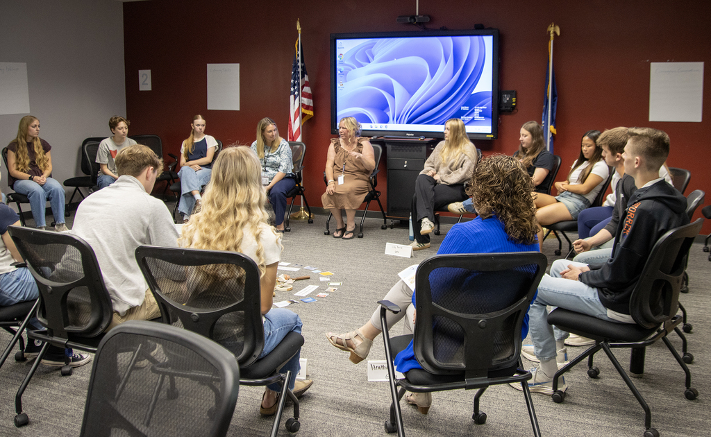 20 students and adults sitting in a circle having a conversation
