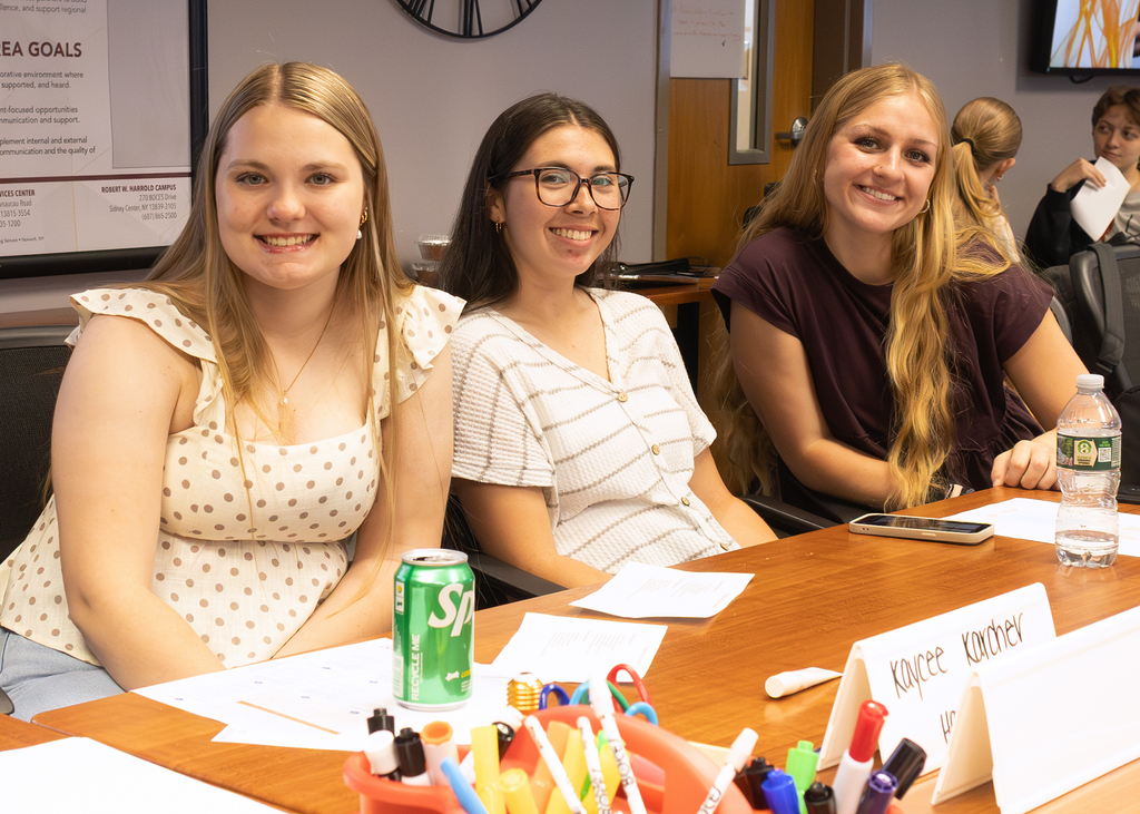 three smiling students at a table