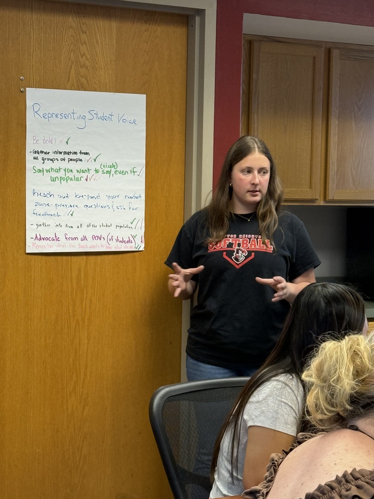 student speaking, pad on the wall with notes