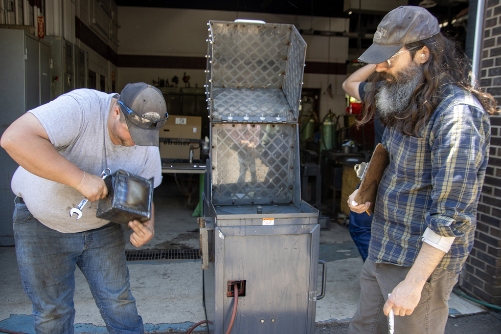 Tyler Reynolds adjusts a steel box for pressure testing as a teacher watches