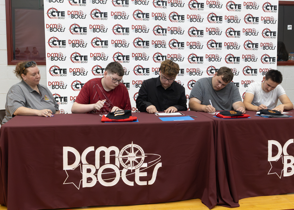 students signing their commitment certificates while an employer watches