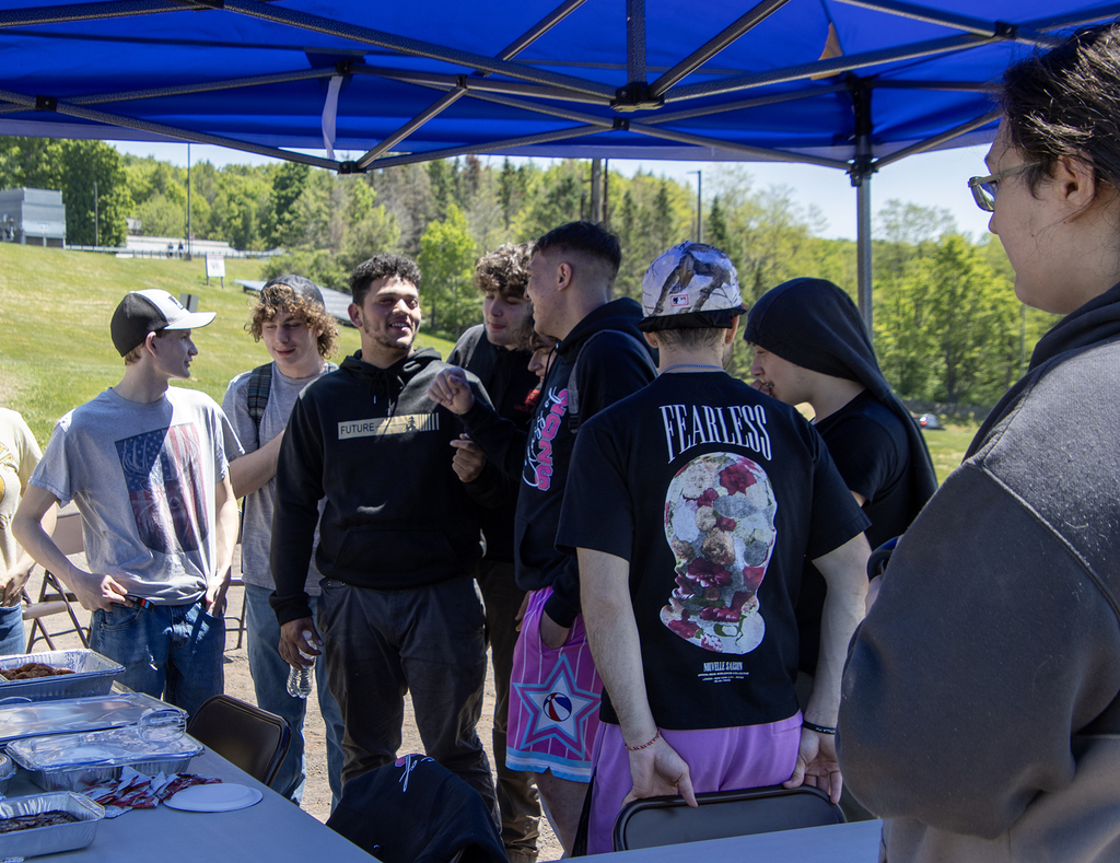 students joke around under a shelter at the picnic