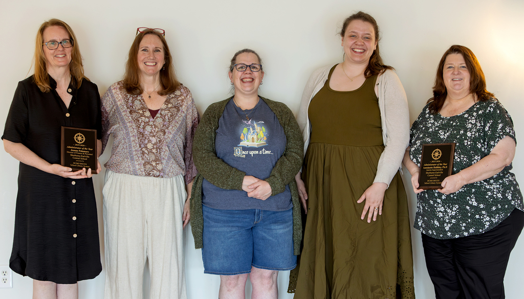 5 women, two holding plaques, pose smiling