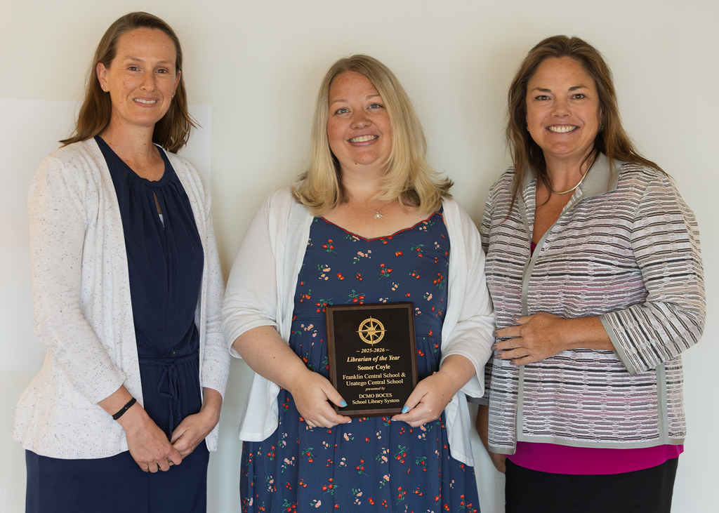 Somer Coyle holds her plaque, flanked by two people