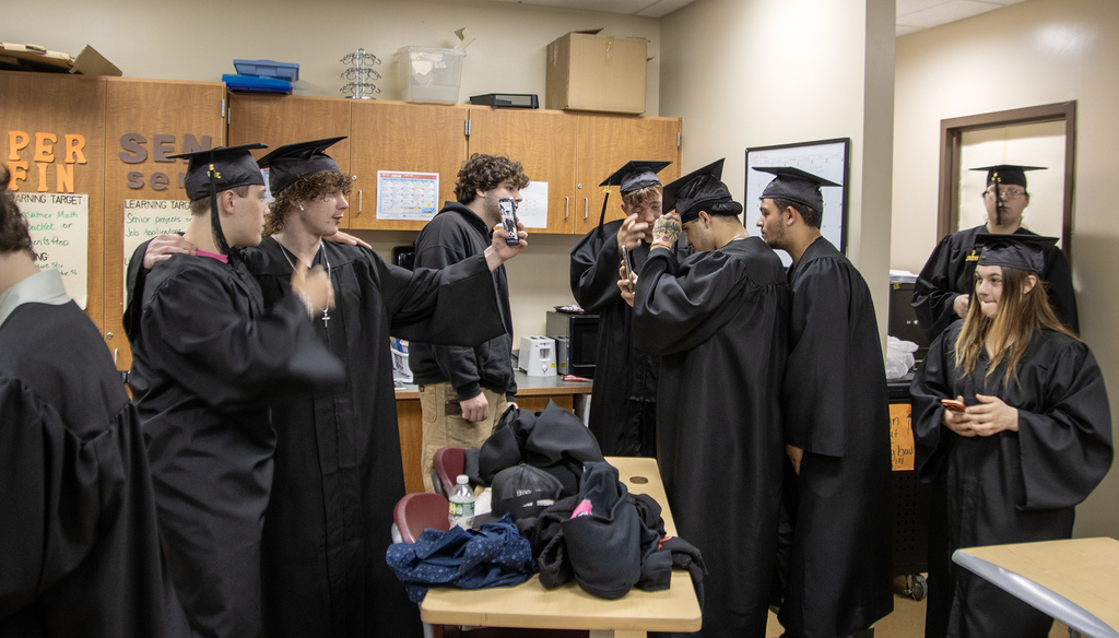 students pose for selfies in their graduation gowns