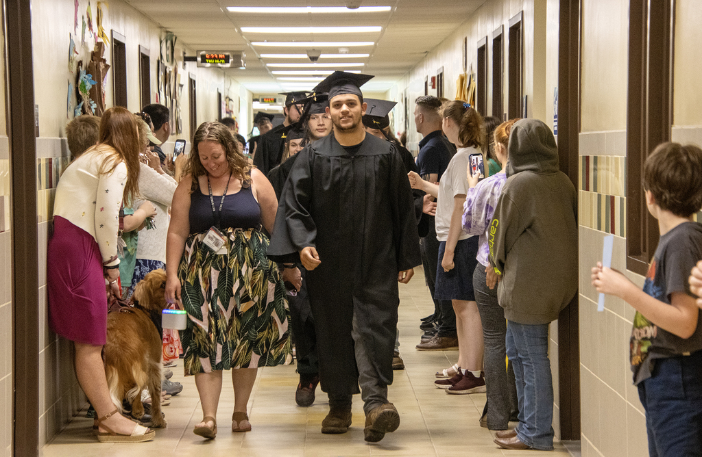 stuident and advisor leading the senior walk down a hallway