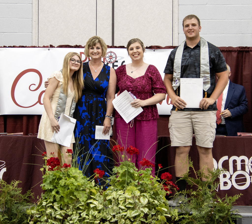 Two scholarship recipients pose with two members of the Ross family.