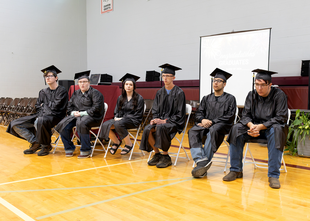 students in caps and gowns sitting in gym