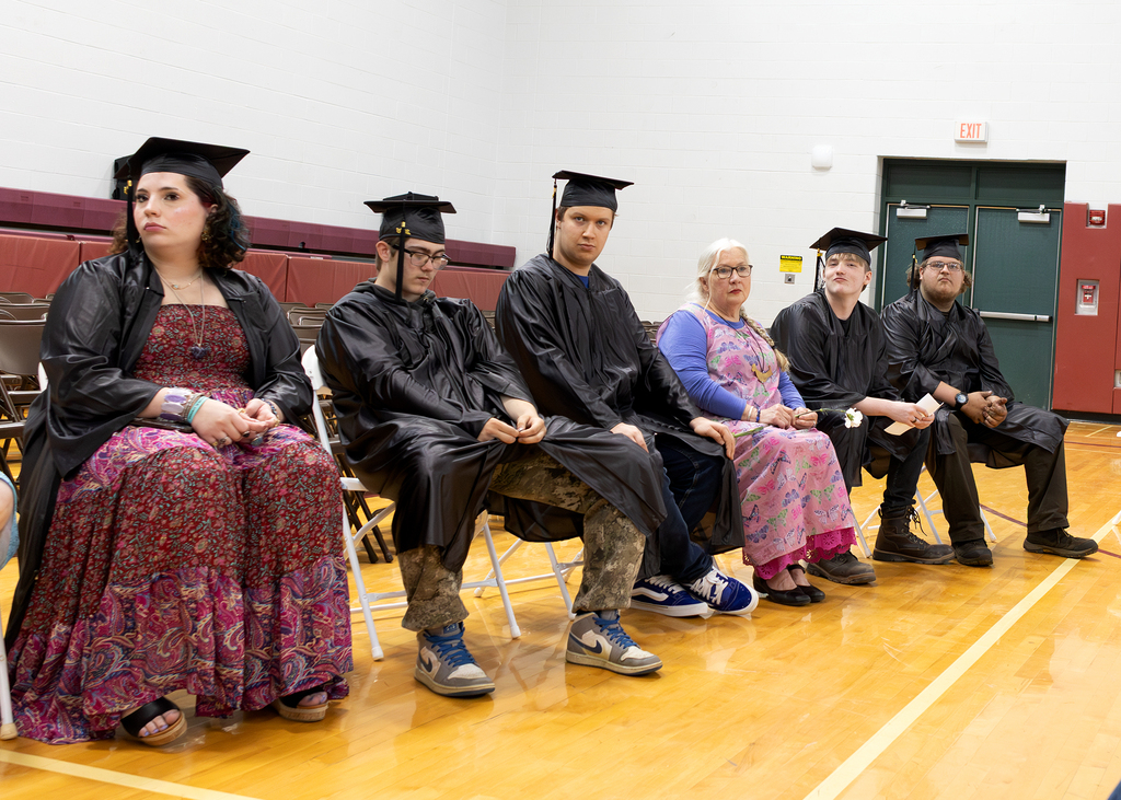 students in caps and gowns sitting in gym