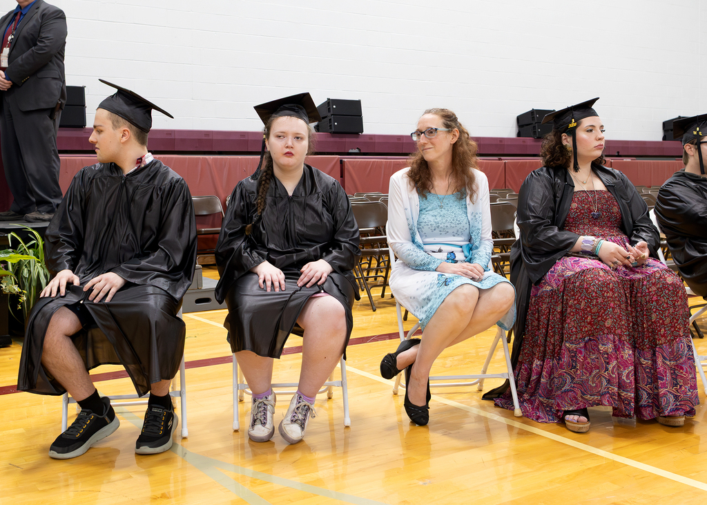 students in caps and gowns sitting in gym