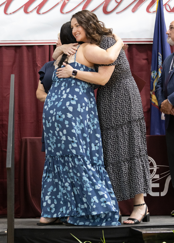 student hugs teacher on stage