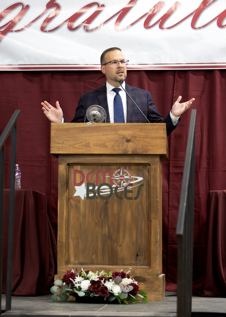 district superintendent gestures while speaking at lectern