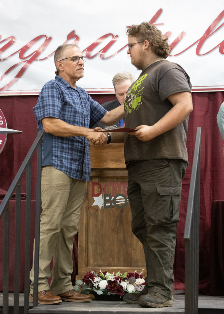 teacher shakes student's hand on stage