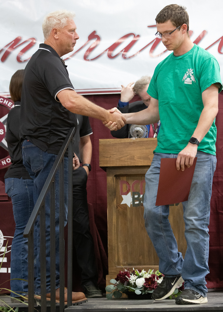 teacher shakes student's hand on stage
