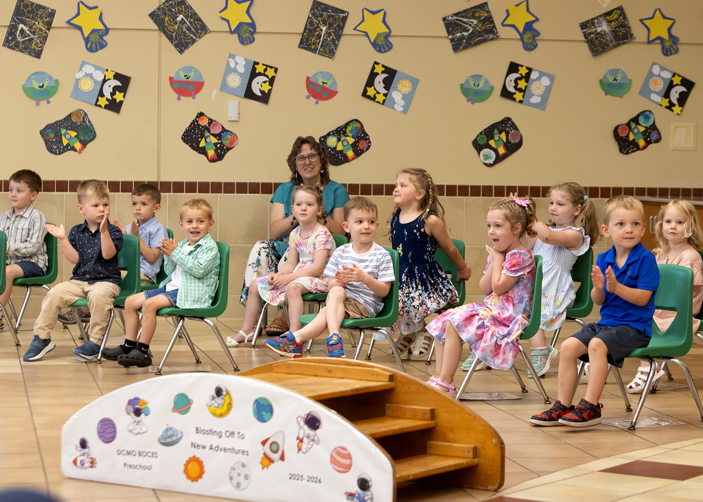 preschool children sitting in chairs and clapping