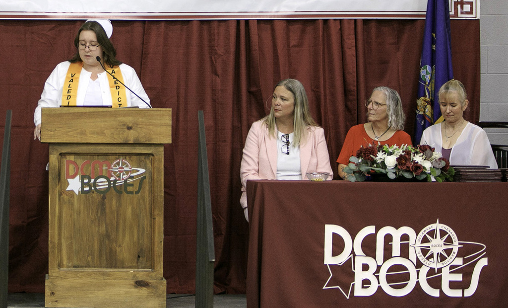 valedictorian speaking from the lectern as three others look on