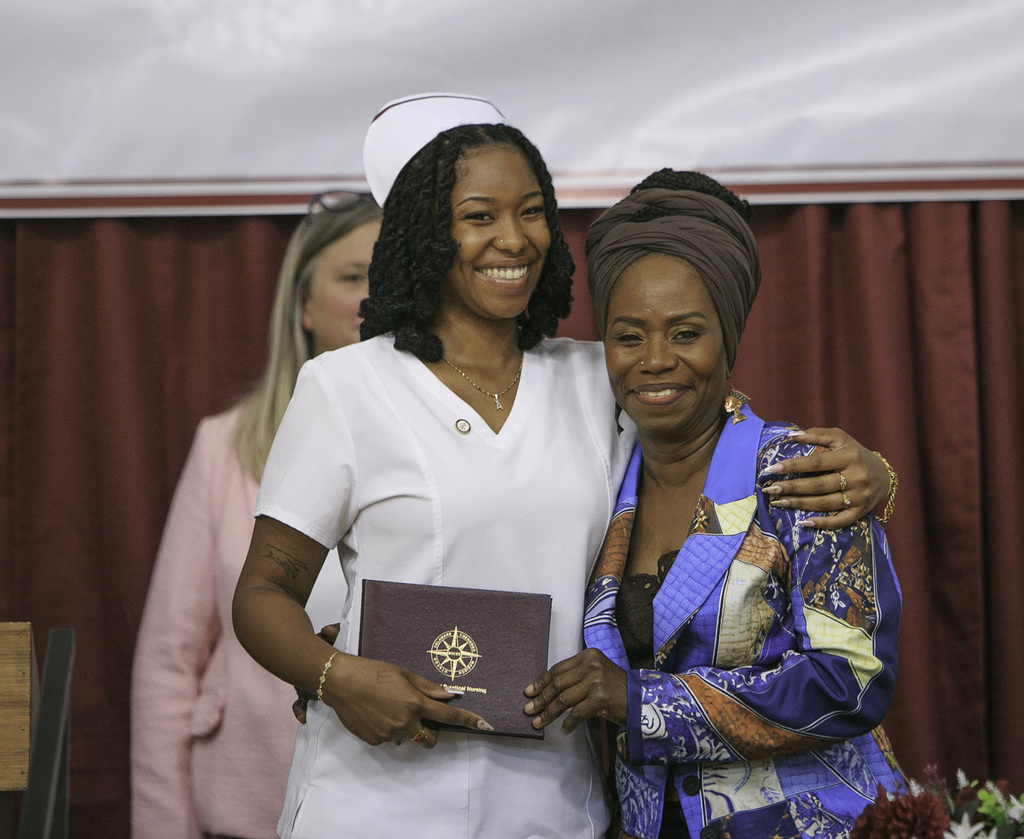 smiling nursing student with mother and diploma