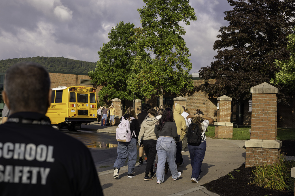 students arrive at Pole Campus; school safety officer shown in foreground; bus is in background