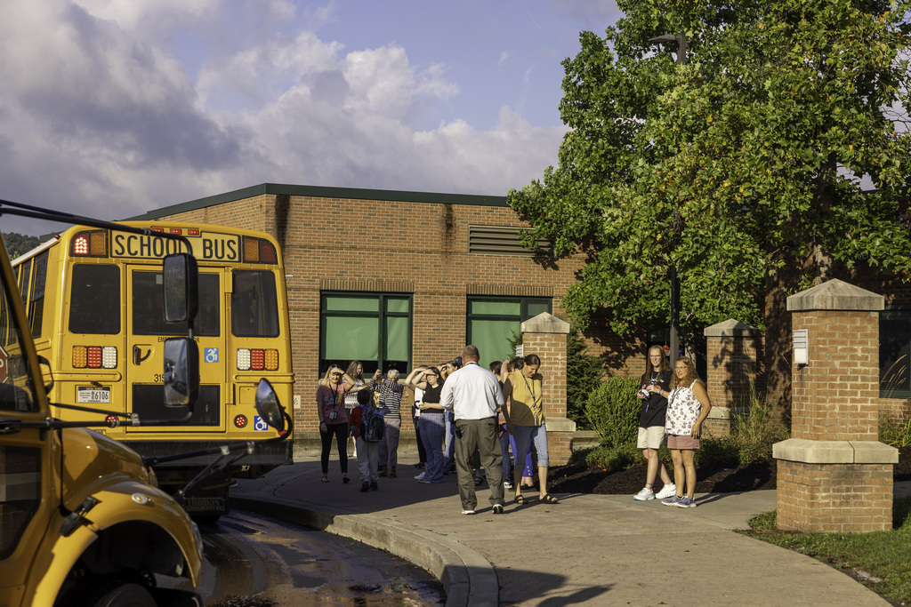 Students arriving at Pole Campus; bus in front, staff there to greet