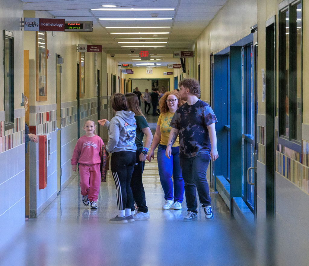 a family is shown coming down the hall, the student is smiling