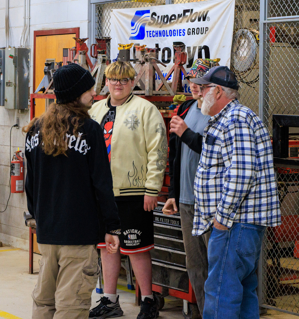 3 young men and an older adult are shown in the auto technologies shop