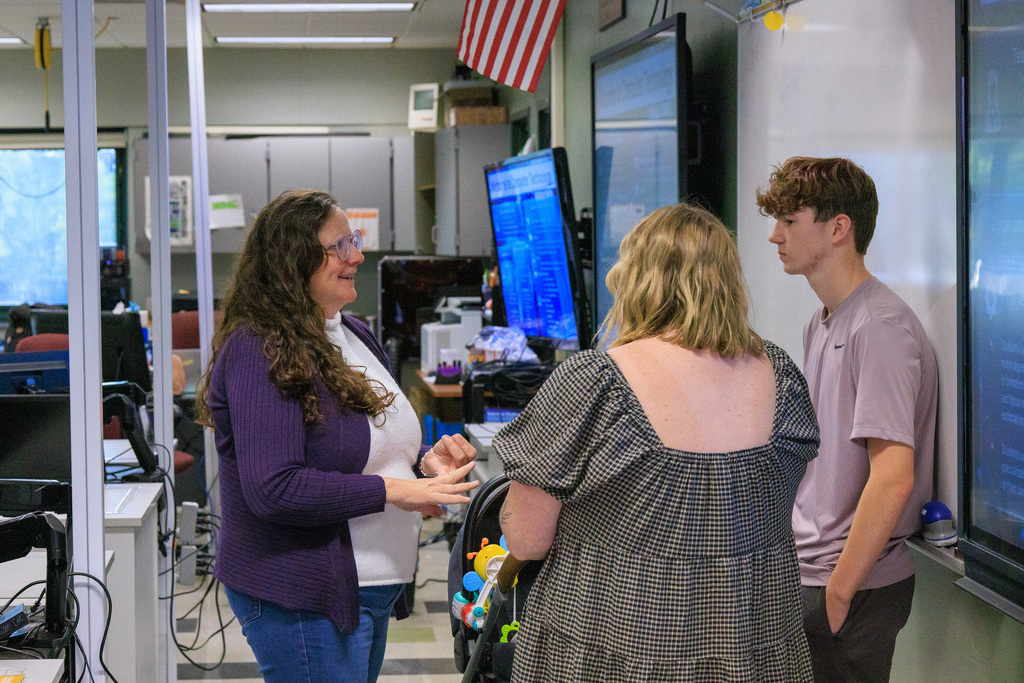 computer tech teacher speaks with a student and a parent in the classroom