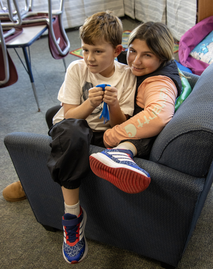 Young boy sitting in lap of smiling teacher aide