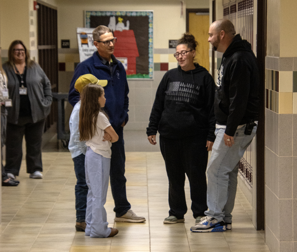 2 children and parents speaking with a teacher in the hallway