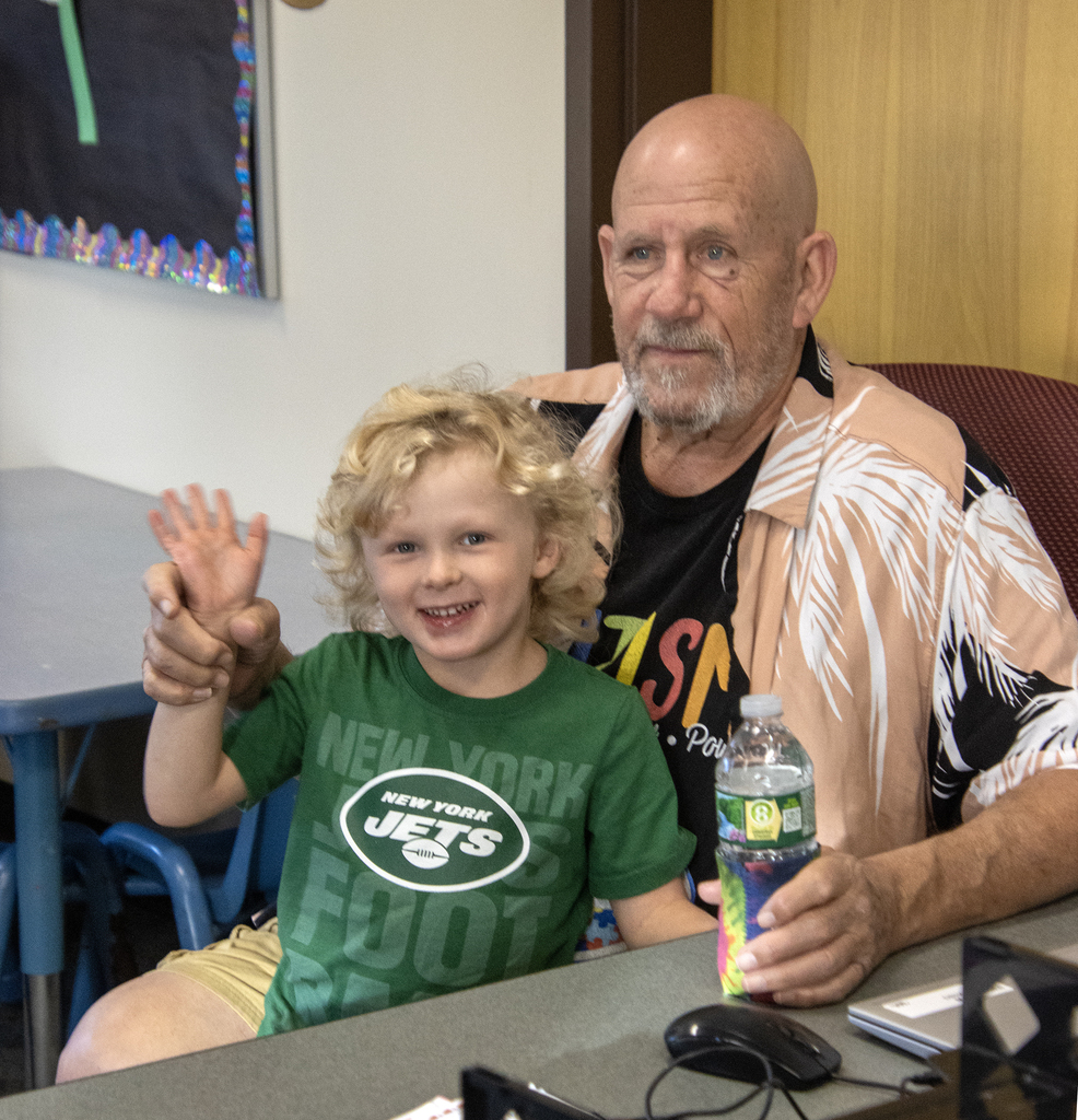 young child waving, sitting in lap of older man