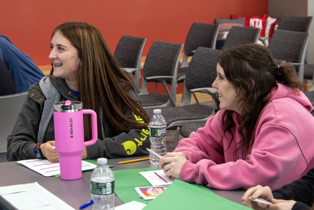 2 students smiling at a speaker