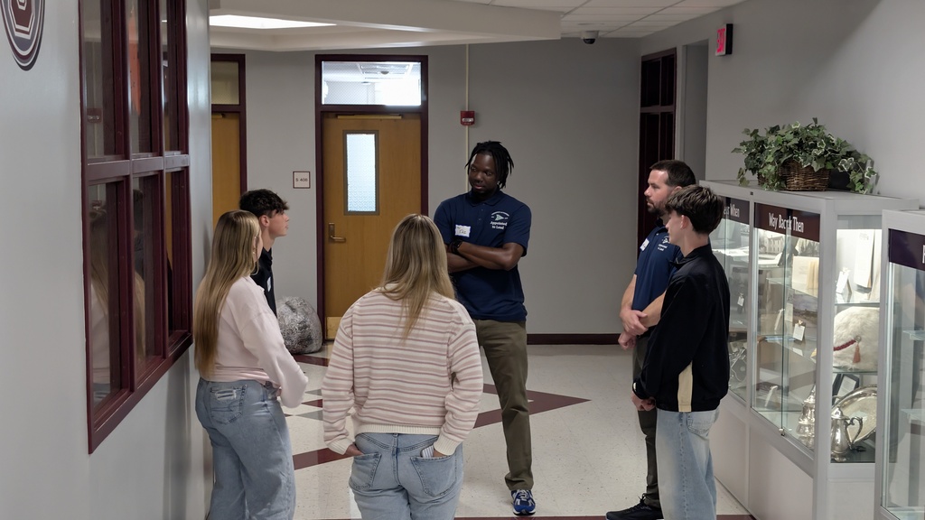 2 facilitators and 4 students stand in a circle talking
