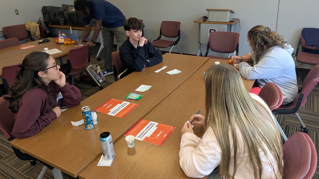 4 students sit at a table in a conference room