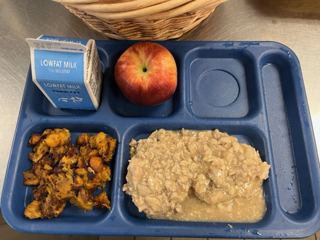 Tray with apple, small carton of milk, vegetable, and something on biscuits