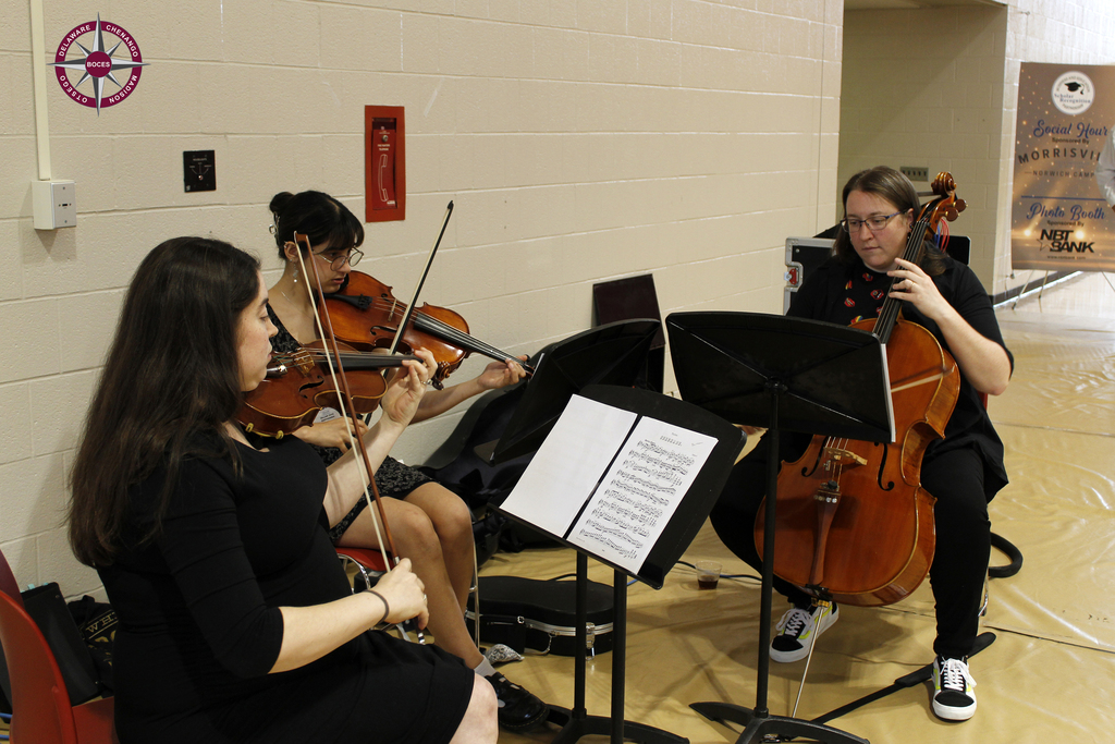 2 adults and a student playing string instruments