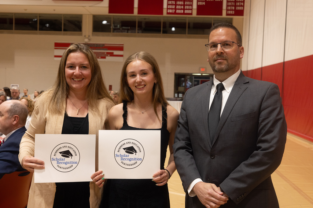 student poses with 2 adults
