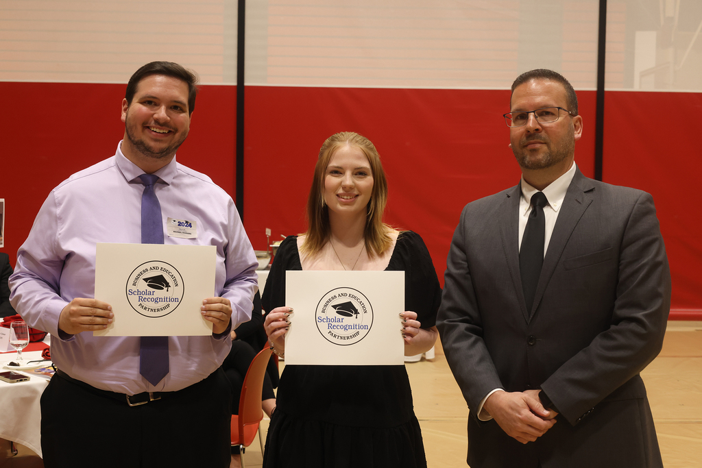 student poses with 2 adults