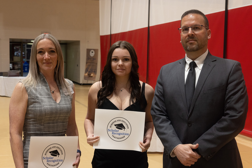 student poses with 2 adults
