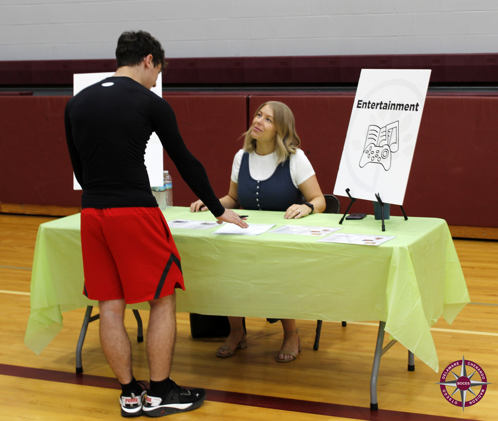 An adult helps a student at the entertainment station