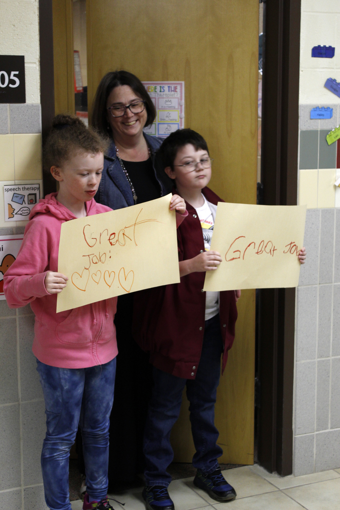 2 students and teacher holding signs