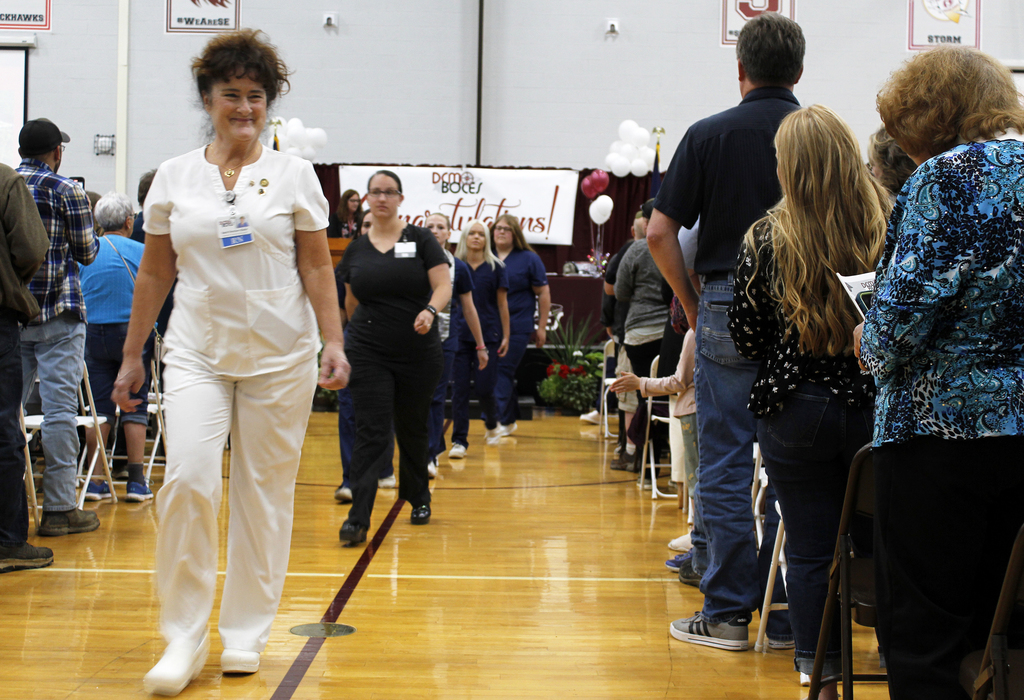 nurse instructor leading students down center aisle