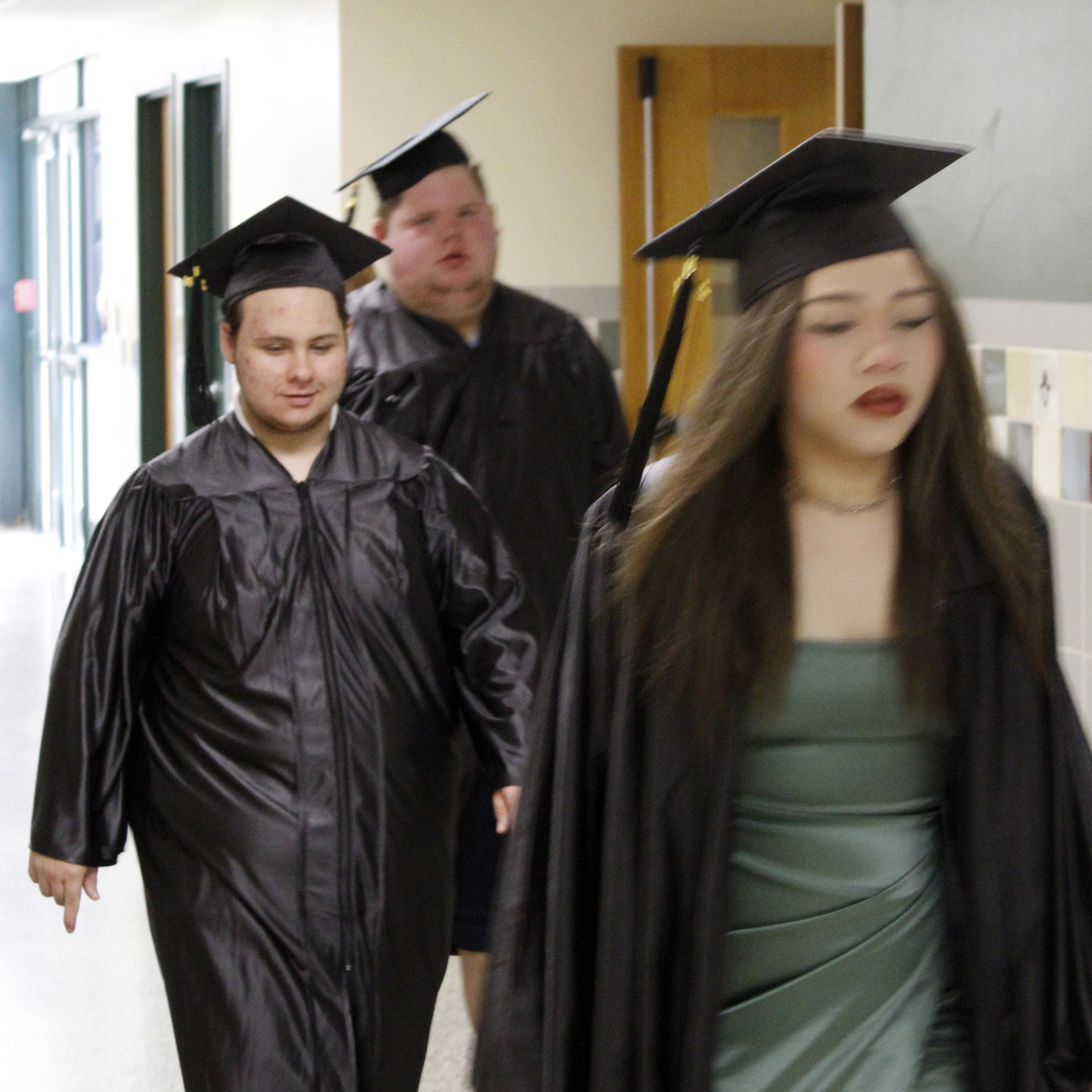 3 students in caps and gowns in hall