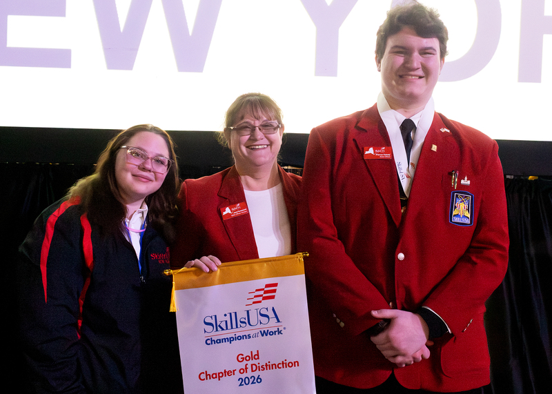 two students and an advisor pose with award banner