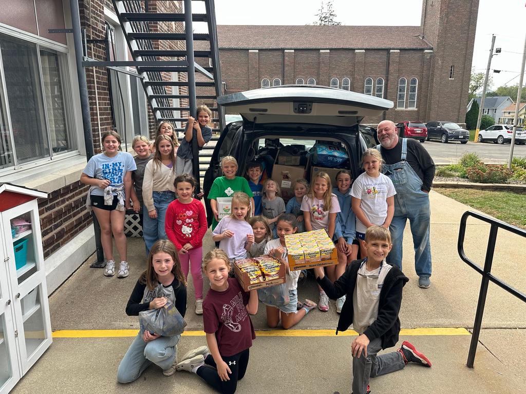 group of students standing in front of a van full of food