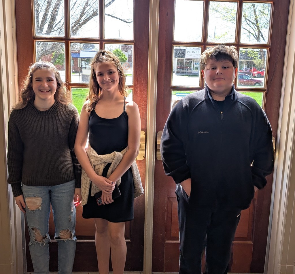 6th Honor Band students standing in front of wood doors with windows