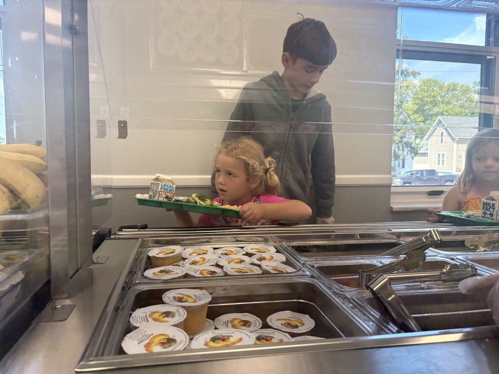 6th grade helping a TK student  at the salad bar