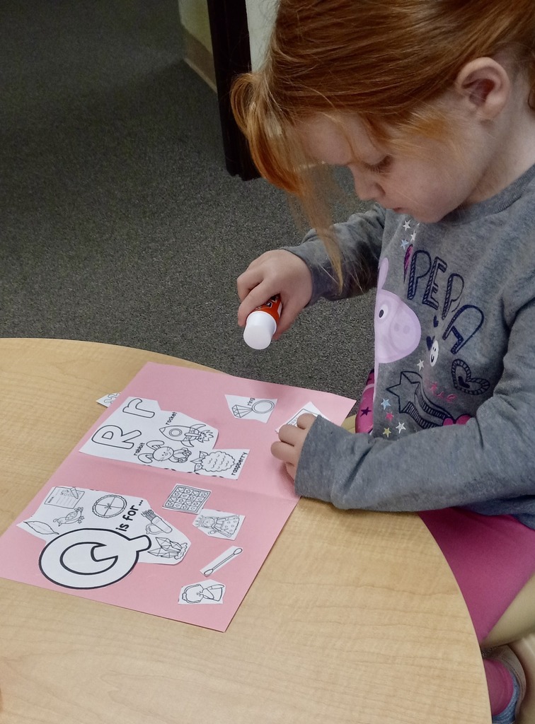 Preschool student with a glue stick and craft paper.