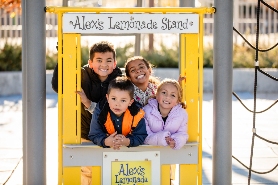 Four students pose for a photo on the playground.