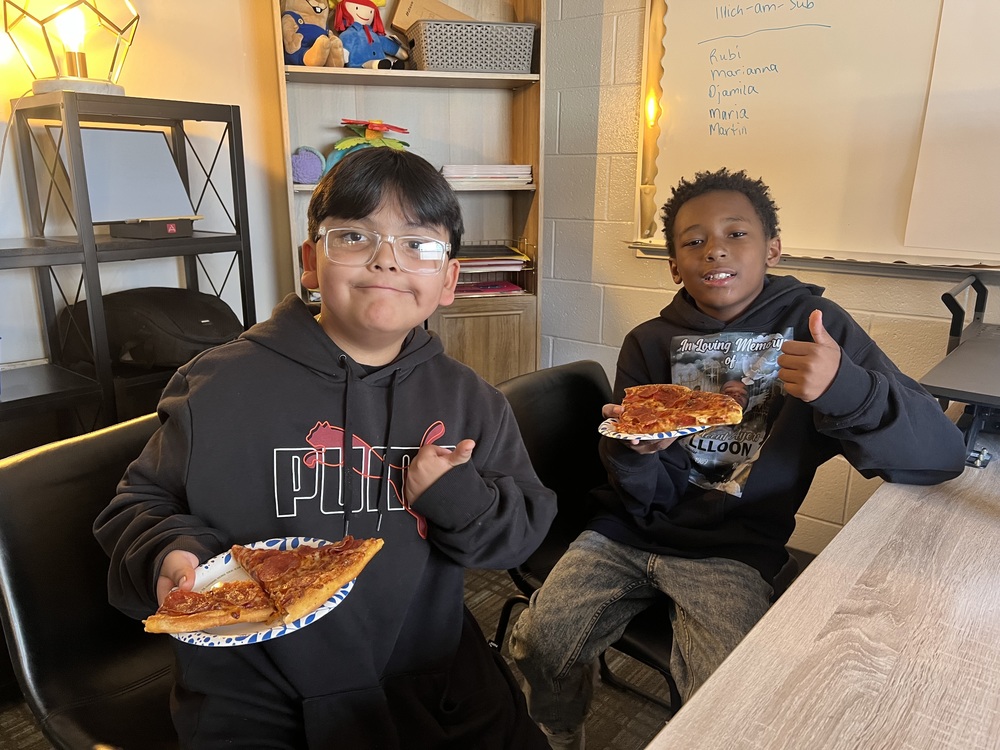 two boys smiling eating pizza