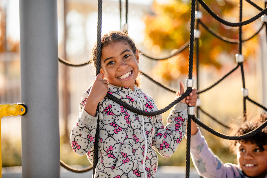 A student smiles while climbing on the playground equipment.
