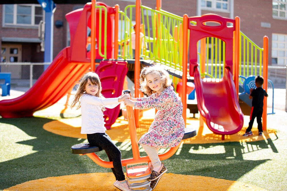 two girls play on a modern teeter-totter at the Palmer ECE Center playground